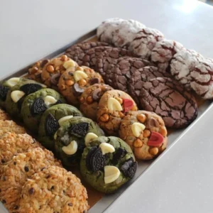 Bandeja de galletas artesanales surtidas con sabores de chocolate, matcha, avena y toppings de Oreo y chispas de chocolate.